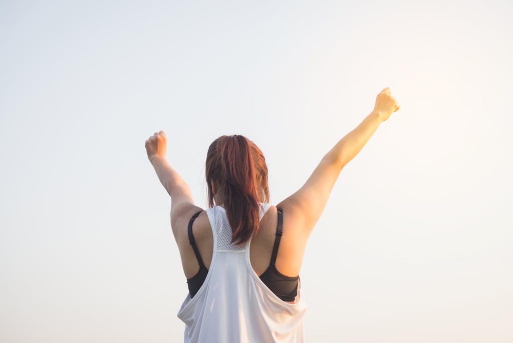 A woman celebrates healthy eating with arms raised in a bright outdoor setting.