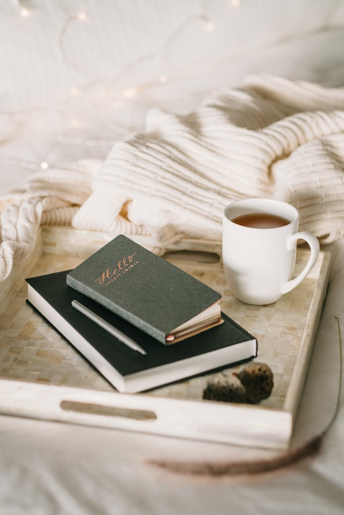 Relaxing setup with a cup of tea and journal on a bed, perfect for a cozy winter afternoon. willpower