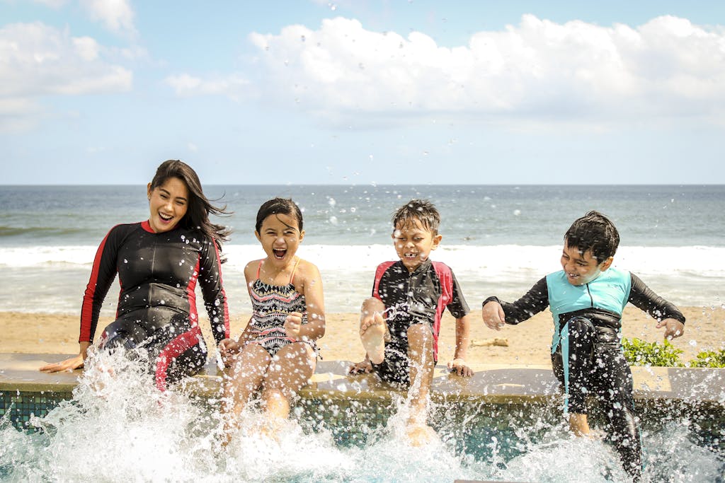 A family having fun splashing water near the seashore on a summer day in Bali, Indonesia.
