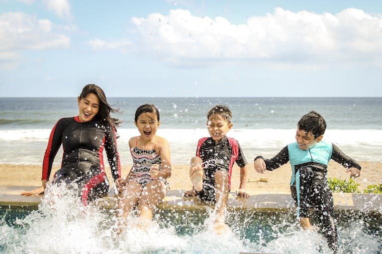 A family having fun splashing water near the seashore on a summer day in Bali, Indonesia.