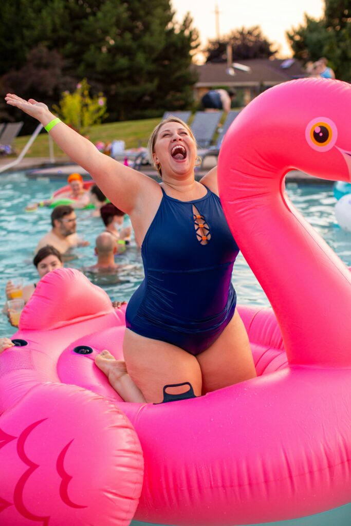 Woman enjoying summer in swimming costume, in inflatable flamingo in pool