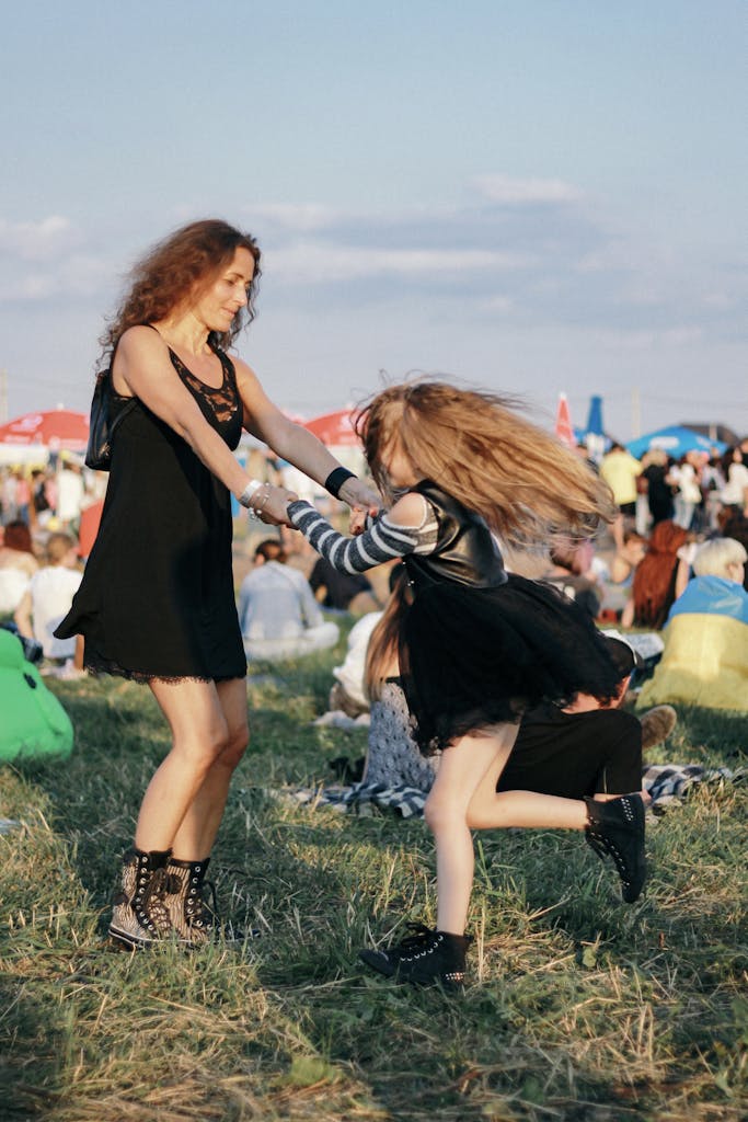 Joyful mother and daughter dancing together in a lively outdoor festival scene.