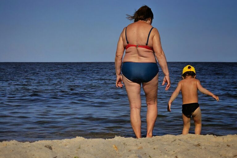 Woman in bikini having fun with child on beach